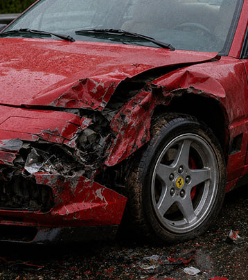 Red Ferrari with visible front-left collision damage before work
