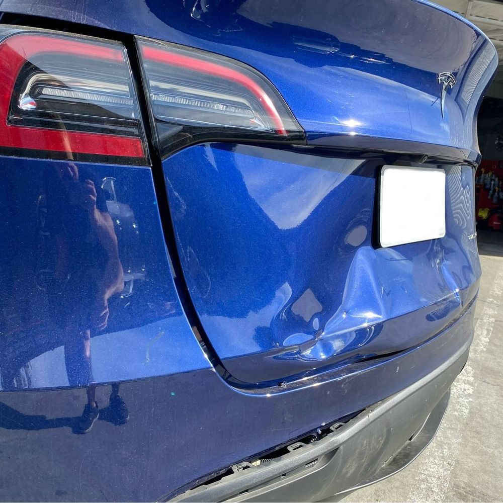 Close view of rear collision damage on a blue Tesla Model Y