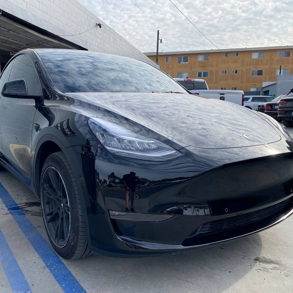 Black Tesla Model Y front exterior in a finished shop photograph