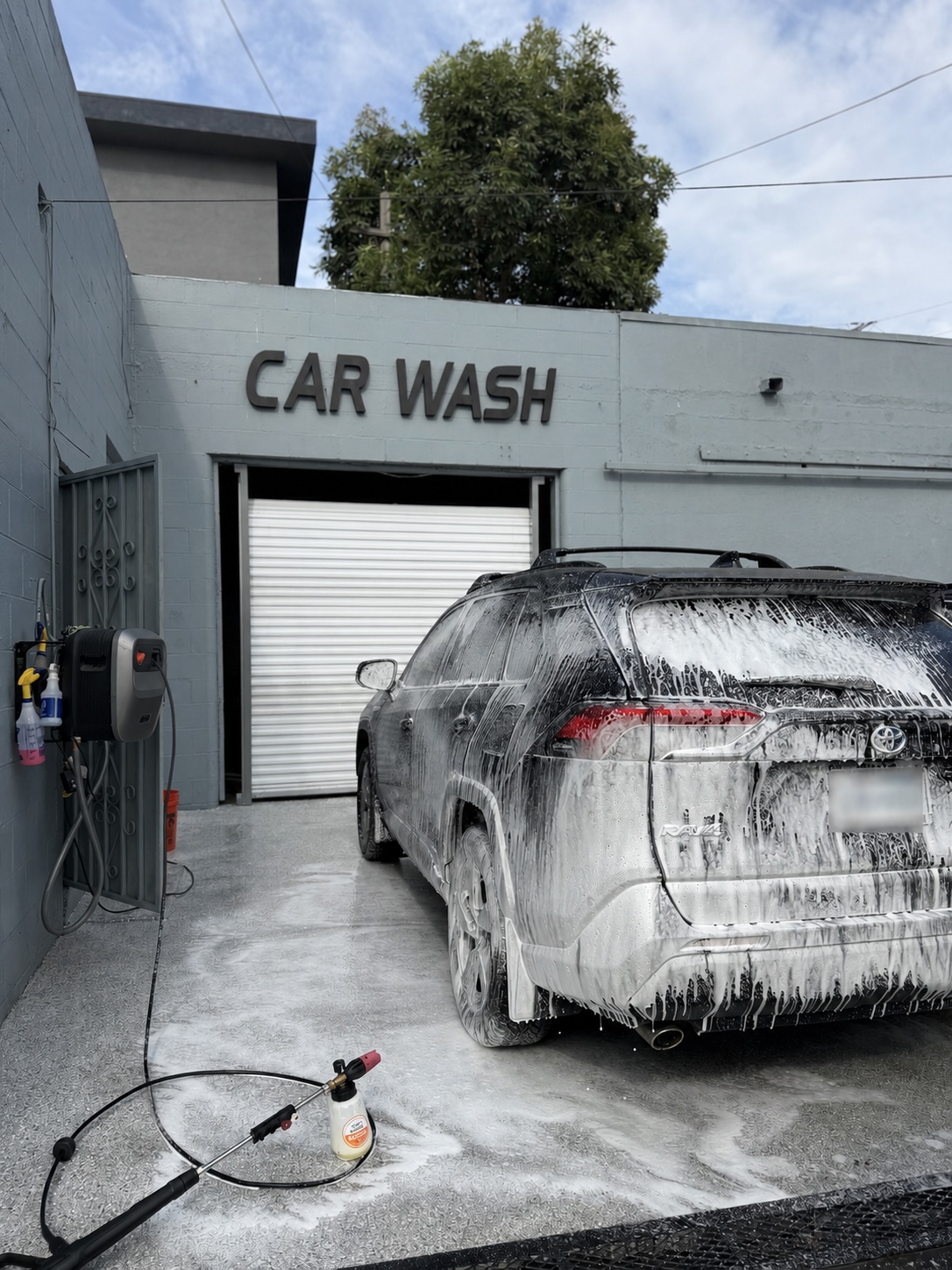 Foam-covered vehicle at the Calibri Motorsport wash station with the license plate obscured for privacy