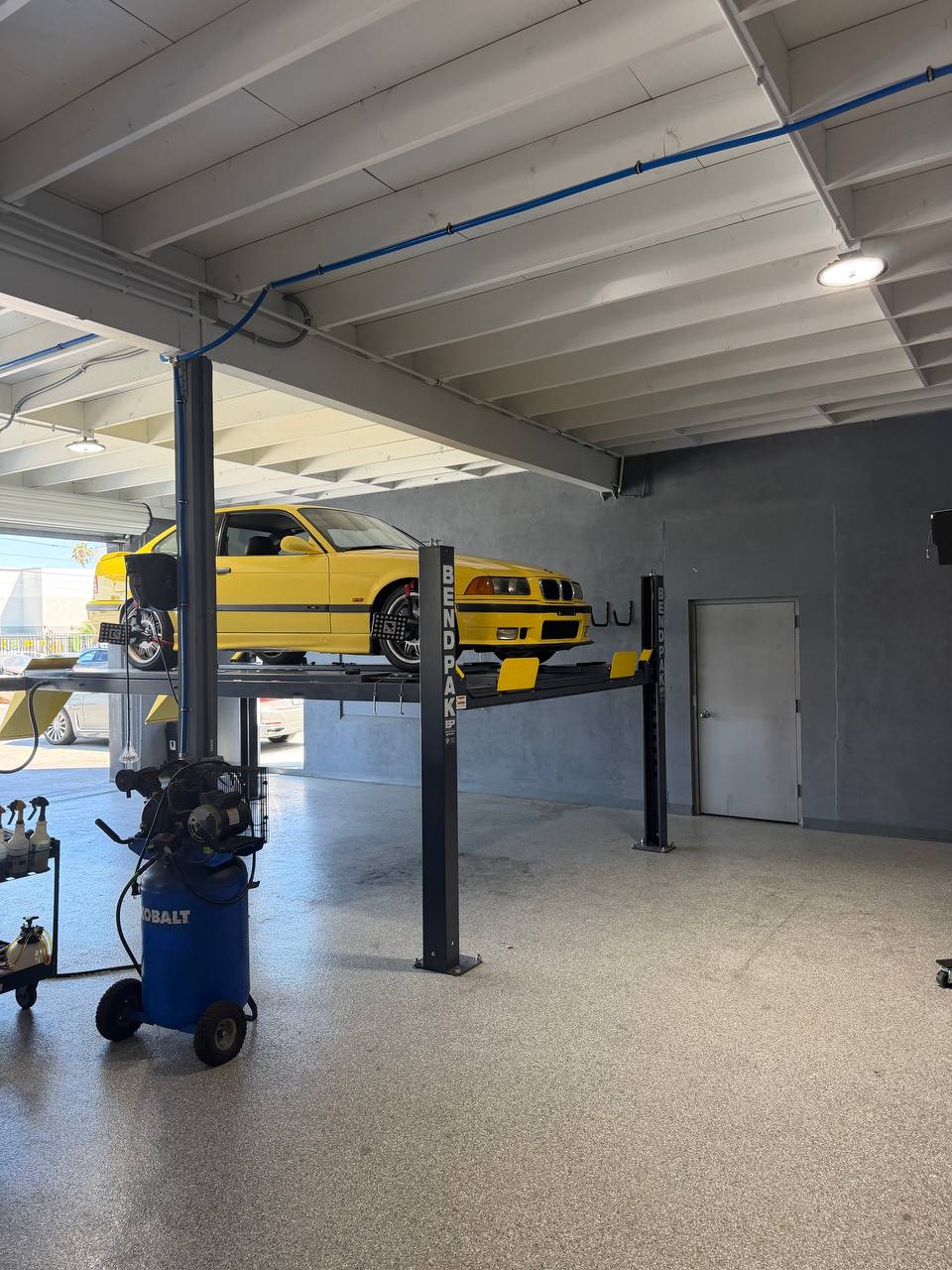 Dakar Yellow BMW E36 M3 on the alignment rack at Calibri Motorsport in Hawthorne