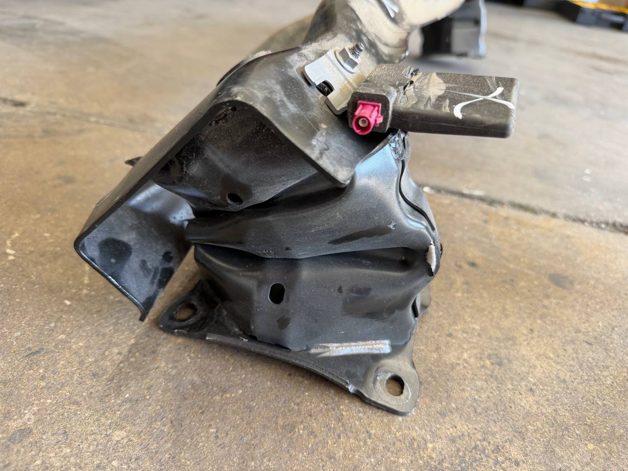 Close-up of a crushed rear mounting component removed from a Volkswagen Taos