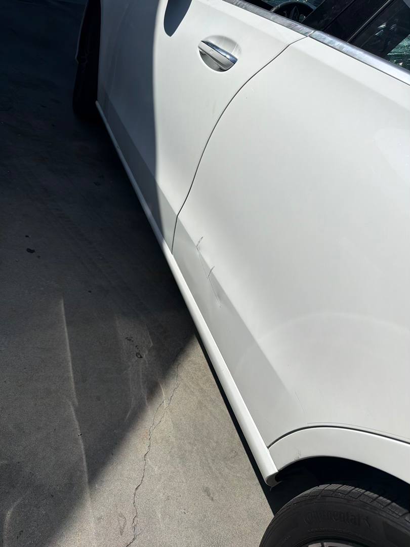 Lower door and rocker damage on a white Mercedes-Benz C300 before refinishing