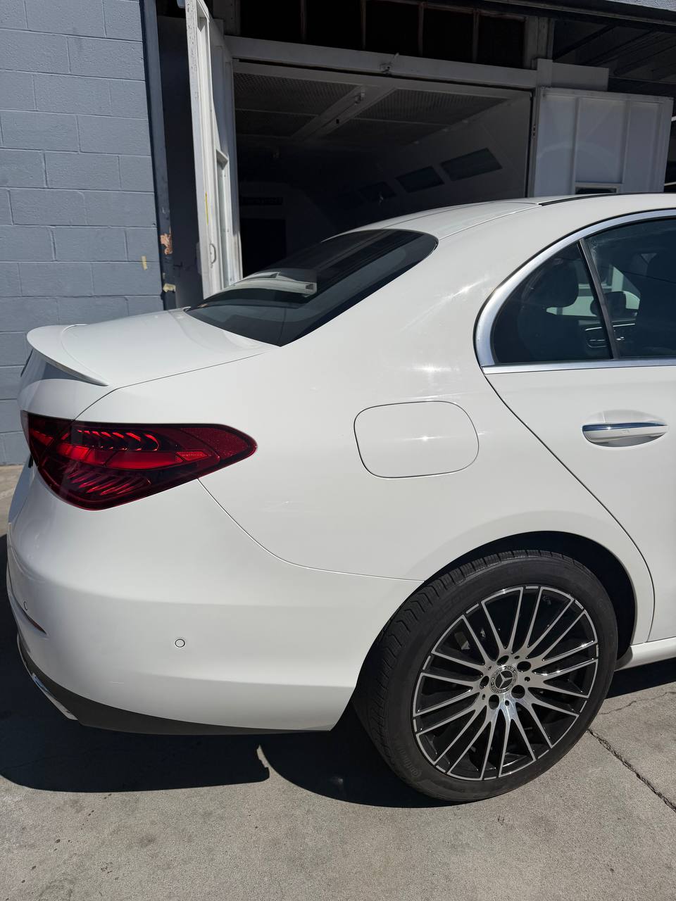 Repaired rear quarter of a white Mercedes-Benz C300 outside the paint booth