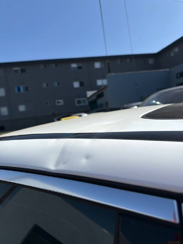 Dent near the roof edge of a white Mercedes-Benz C300 before body repair