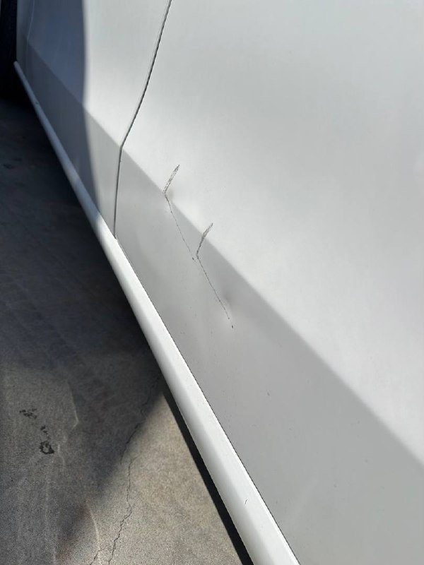 Scrapes and creases on a white Mercedes-Benz C300 side panel before repair