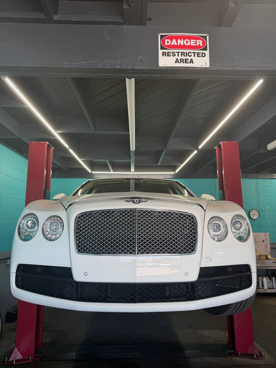 White Bentley sedan raised on a lift inside Calibri Motorsport