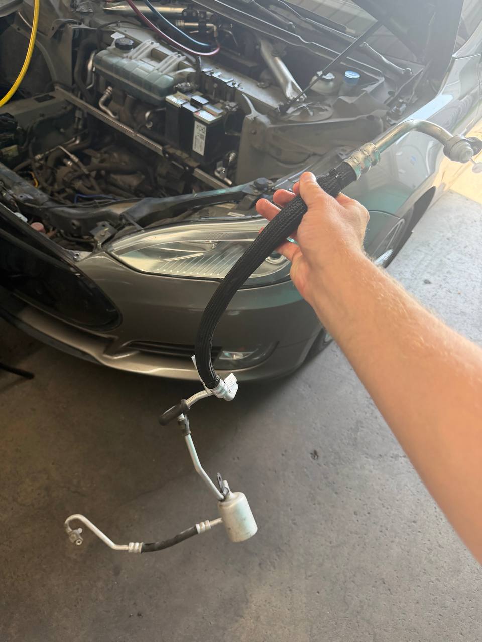 Removed Tesla Model S refrigerant line held beside the open front compartment