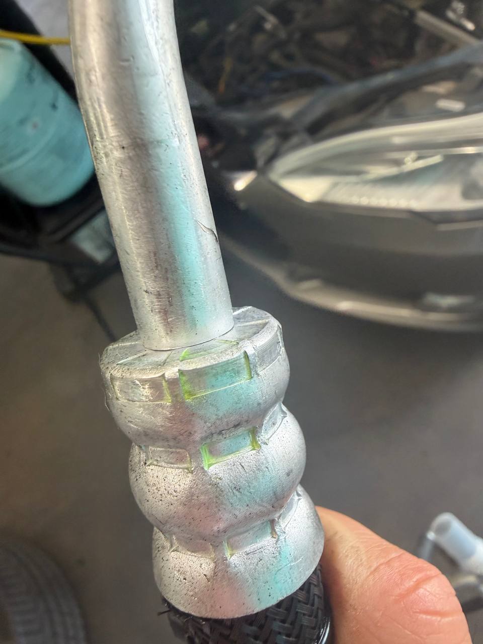 Fluorescent leak-detection dye visible on a Tesla Model S air-conditioning line fitting