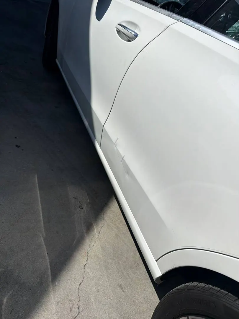 Lower door and rocker damage on a white Mercedes-Benz C300 before refinishing