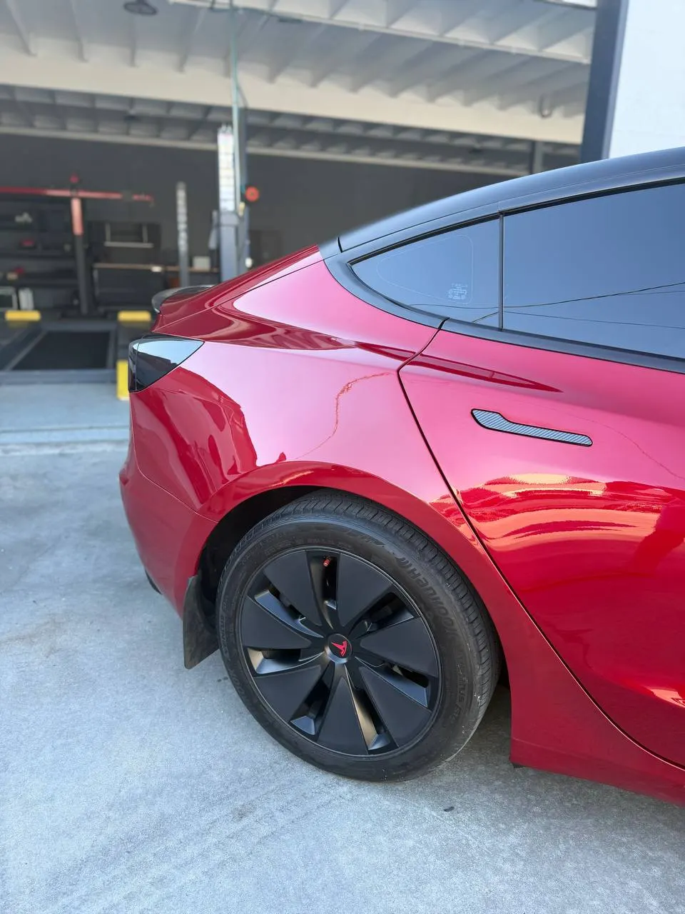 Finished red Tesla Model 3 rear quarter and bumper in daylight