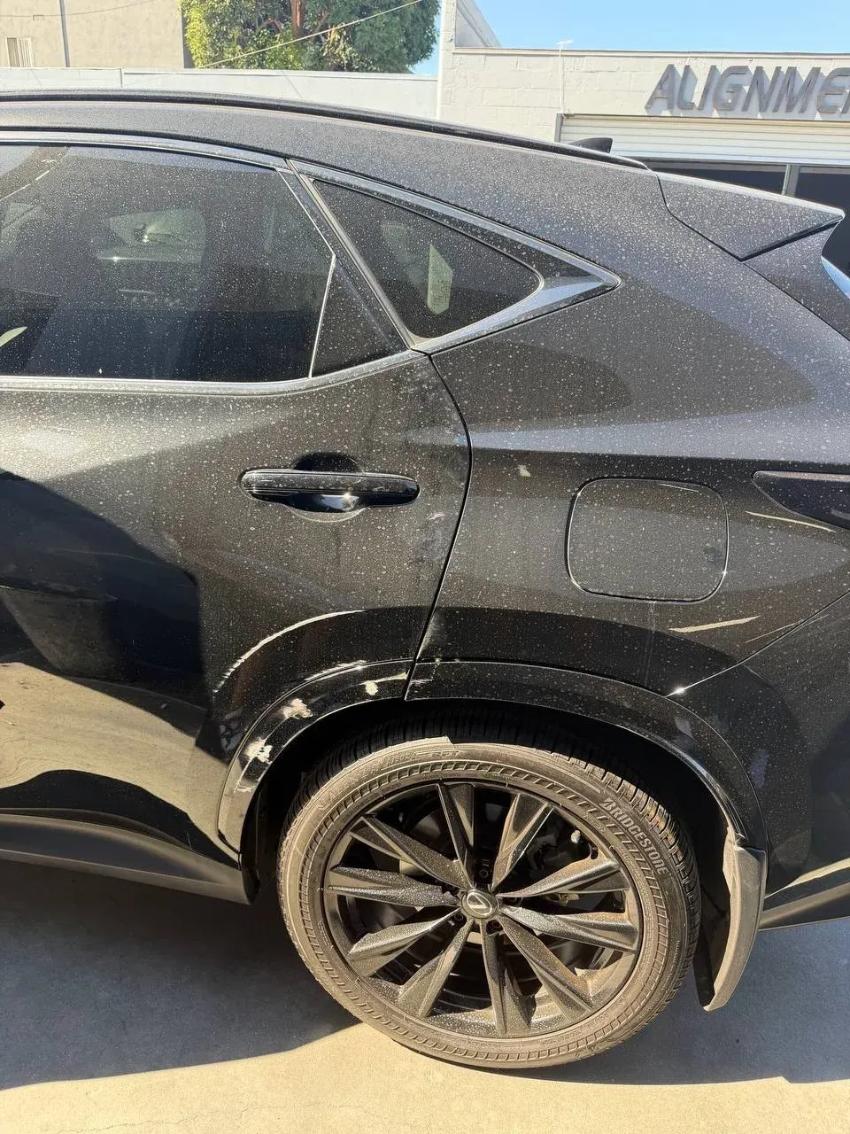 Scratches across the rear door and wheel-arch trim of a dark vehicle
