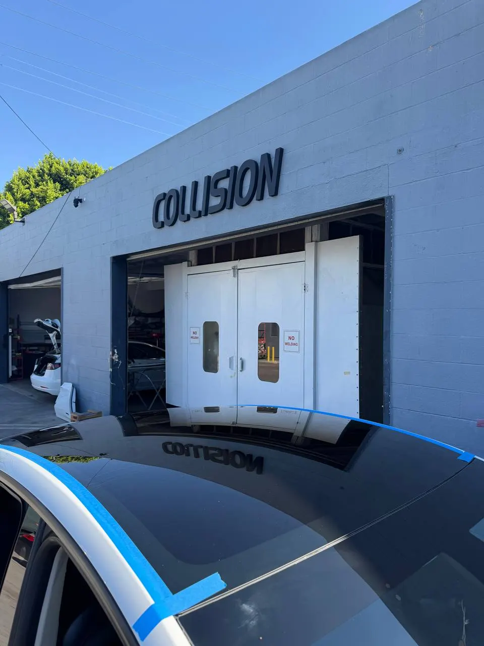 Roof glass in position on a white Tesla Model Y with blue tape along the perimeter.