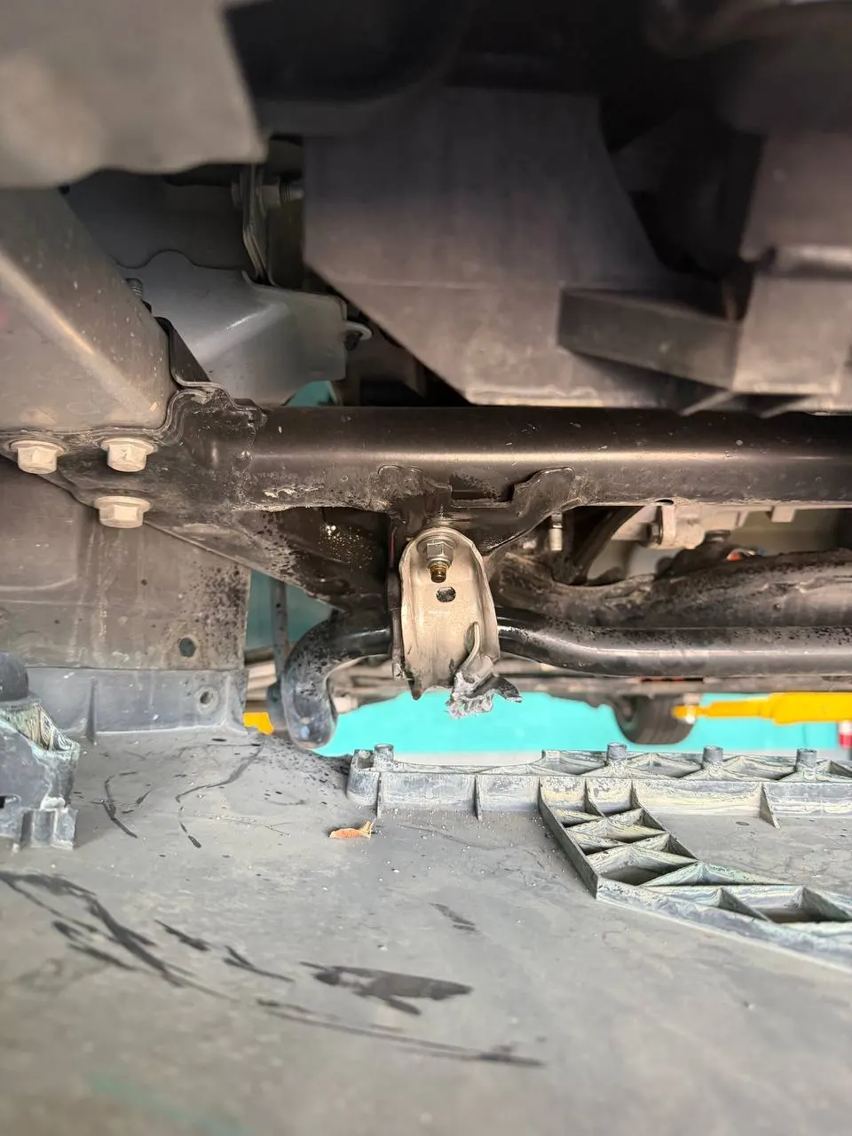 Bent sway-bar bracket area under a Tesla Model 3 after a pothole impact