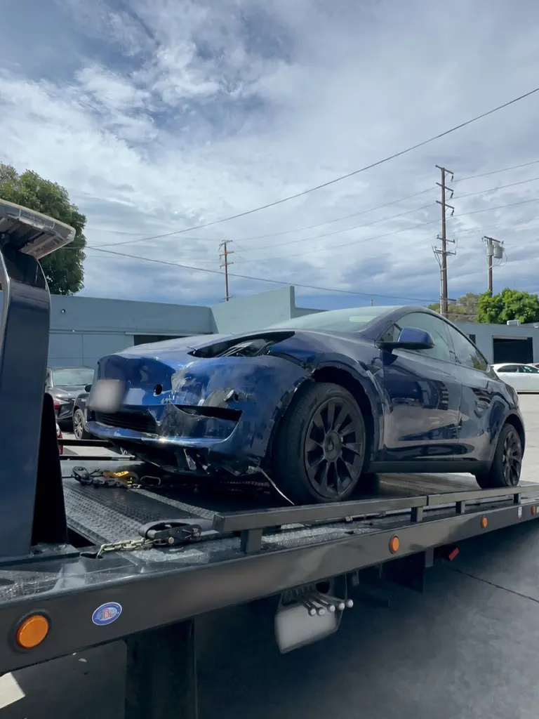 Collision-damaged Tesla Model Y arriving at Calibri Motorsport on a flatbed