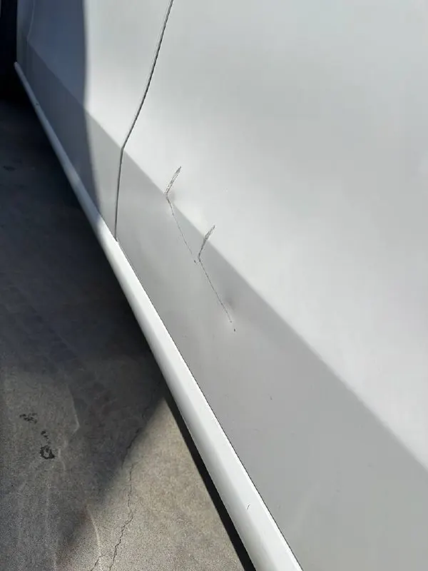 Scrapes and creases on a white Mercedes-Benz C300 side panel before repair