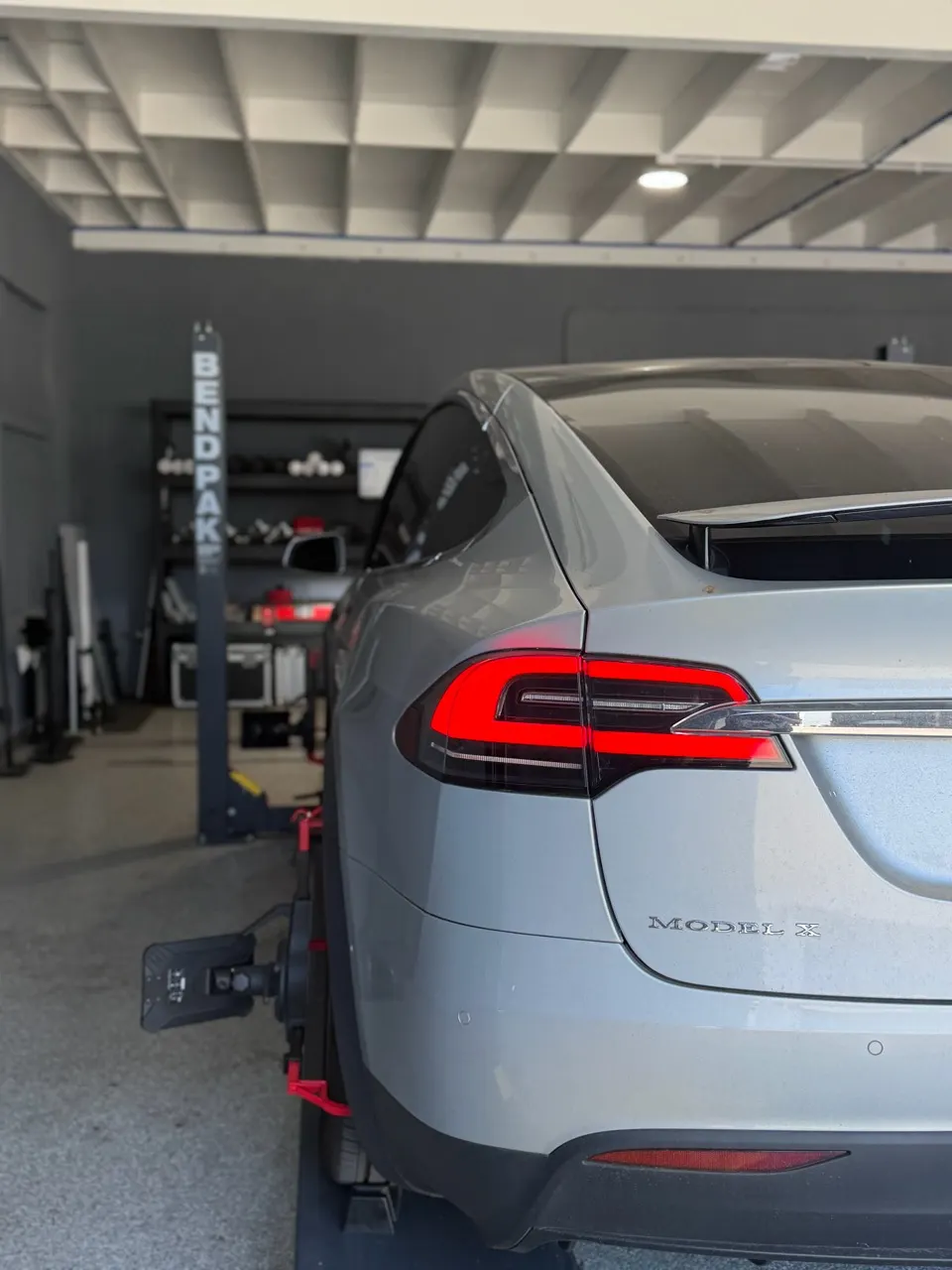 Rear view of Tesla Model X on the alignment rack with a target attached to the rear wheel