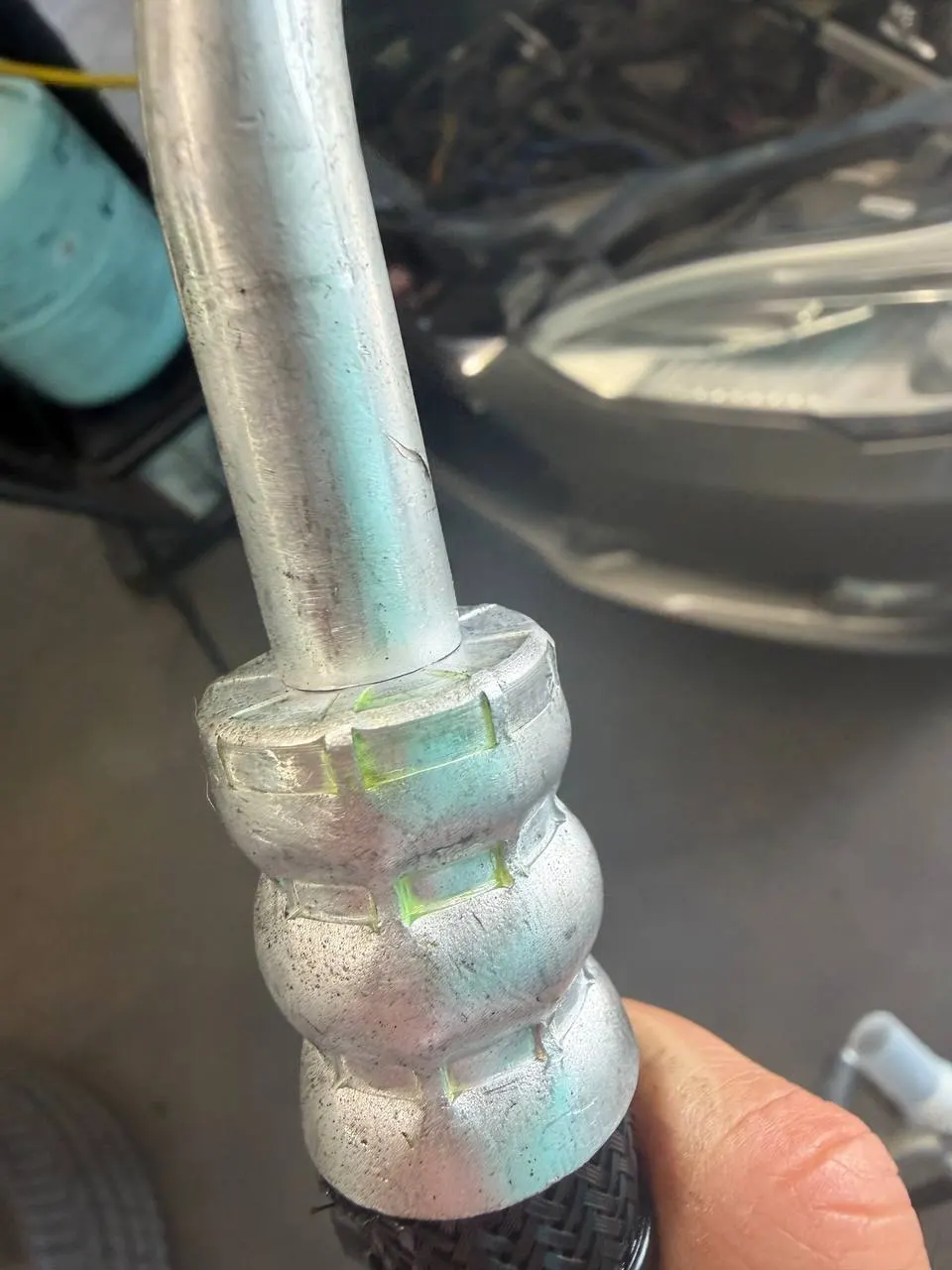 Fluorescent leak-detection dye visible on a Tesla Model S air-conditioning line fitting