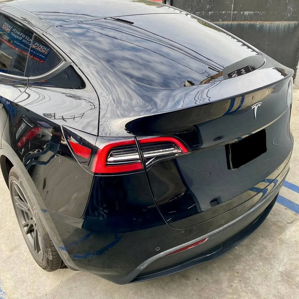 Rear view of a black Tesla Model Y after exterior work