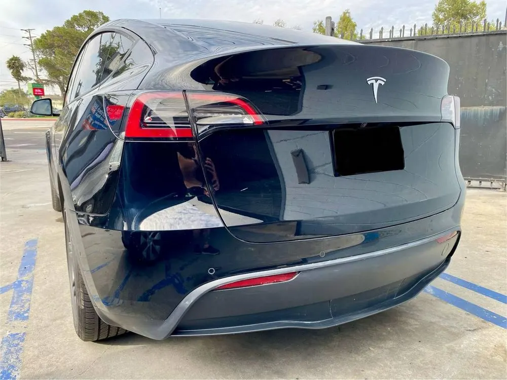 Three-quarter rear view of a black Tesla Model Y after exterior work