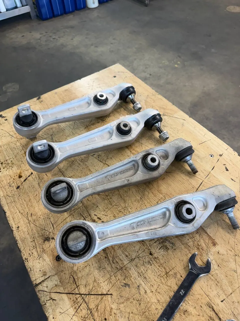 Tesla Model 3 control arms arranged on a workbench during suspension repair