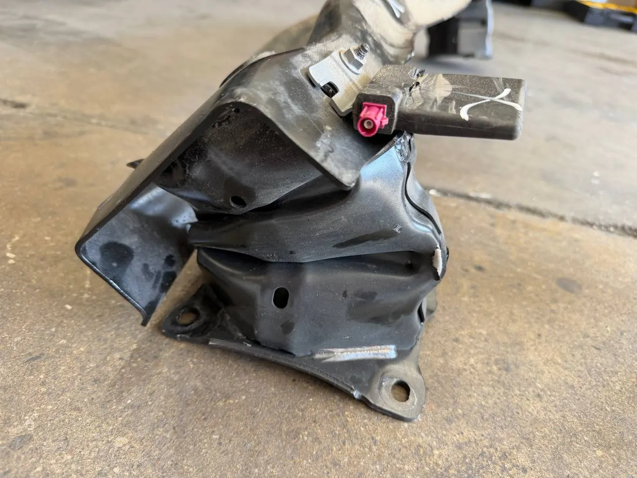 Close-up of a crushed rear mounting component removed from a Volkswagen Taos