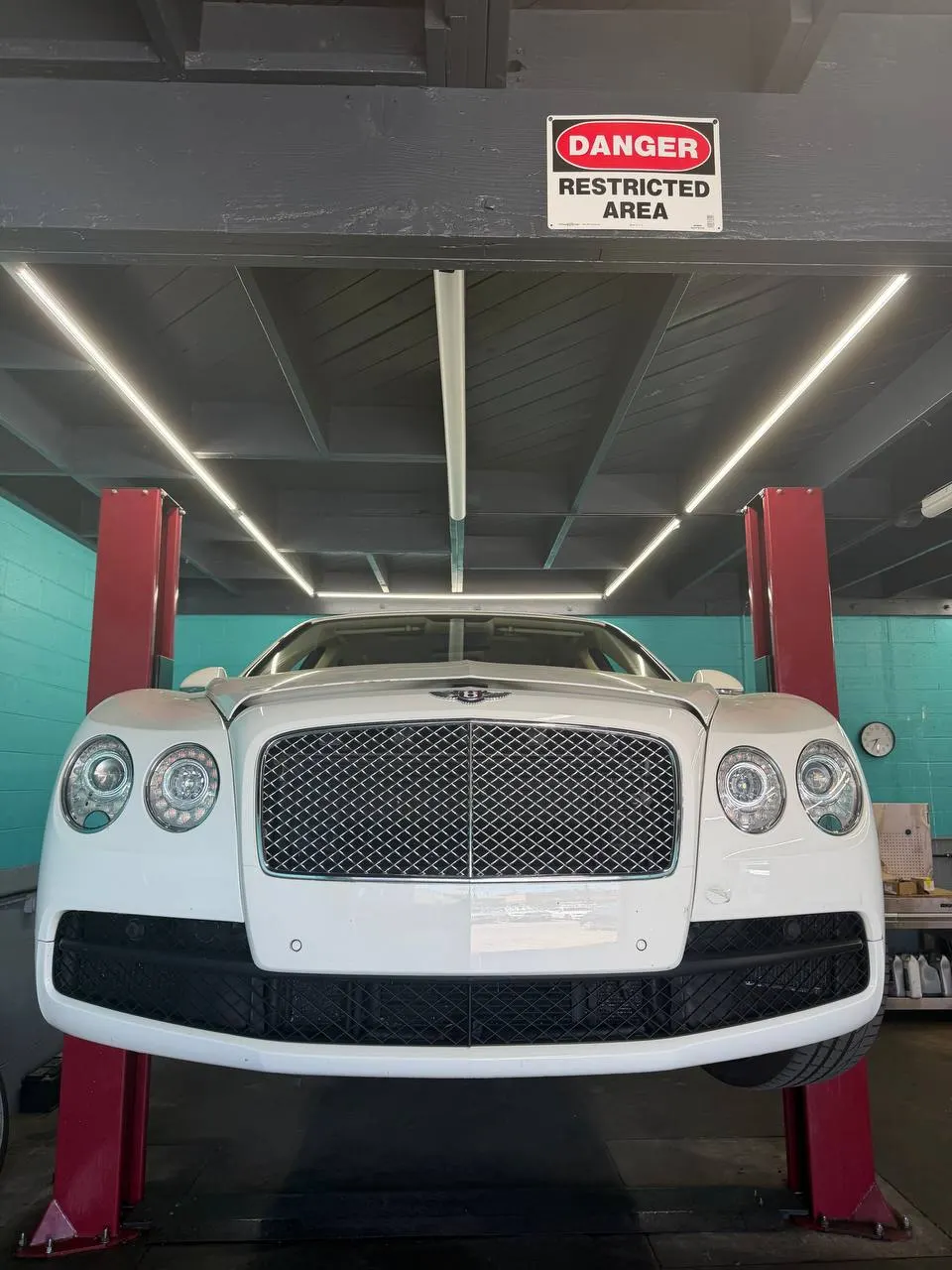 White Bentley sedan raised on a lift inside Calibri Motorsport