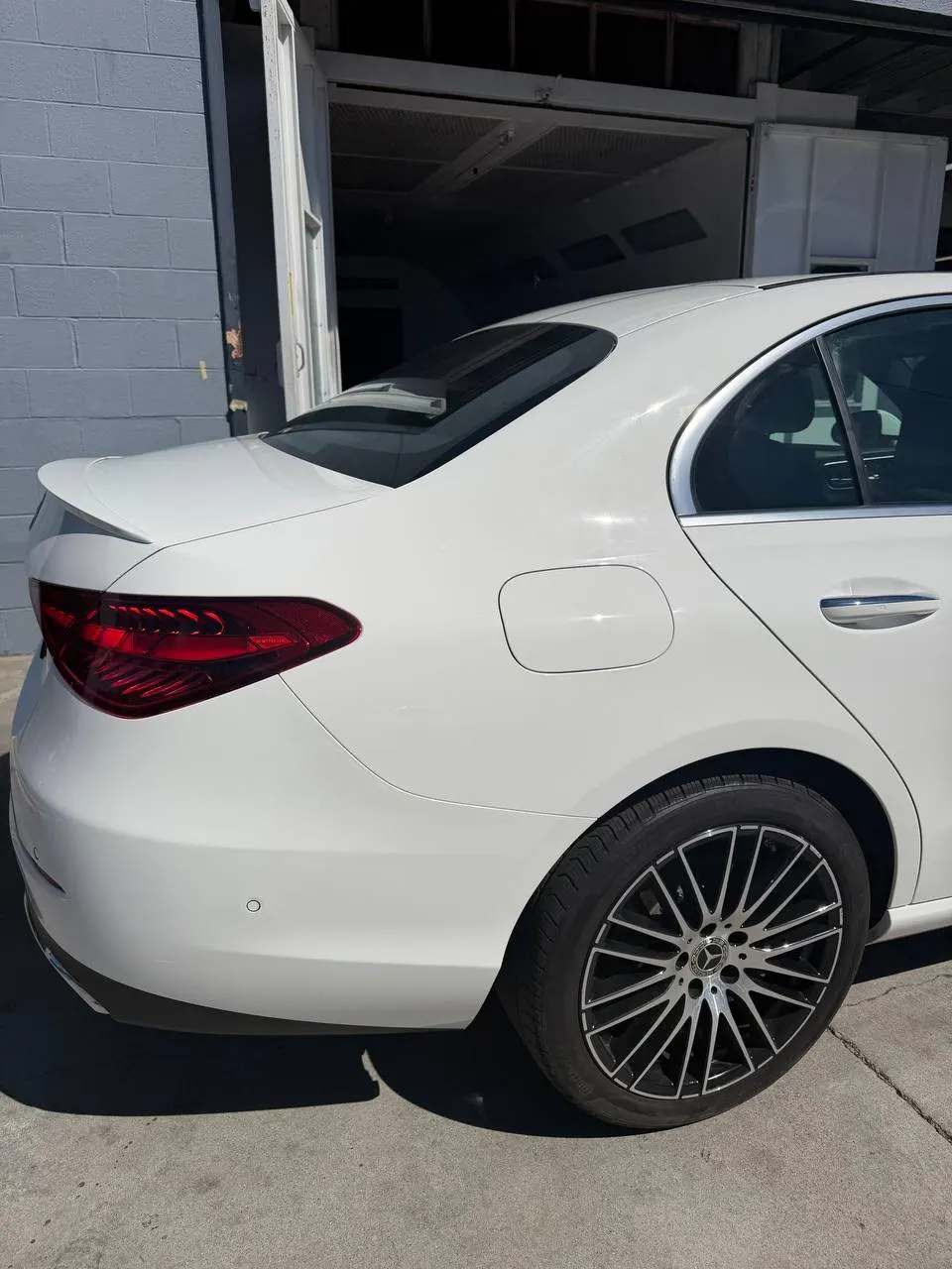 Repaired rear quarter of a white Mercedes-Benz C300 outside the paint booth