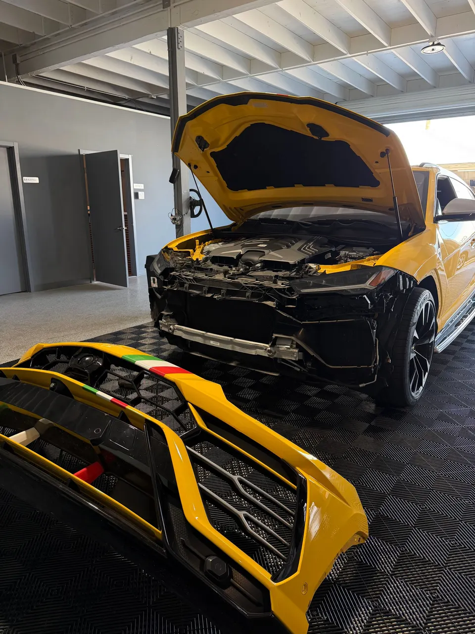 Yellow Lamborghini Urus with its hood raised and front bumper removed at Calibri Motorsport in Hawthorne