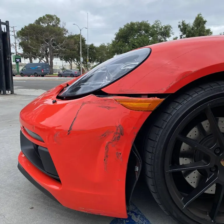 Visible front-corner collision damage on a Porsche photographed at Calibri Motorsport