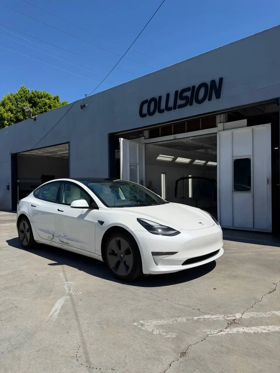 White Tesla Model 3 with visible driver-side collision damage at Calibri Motorsport